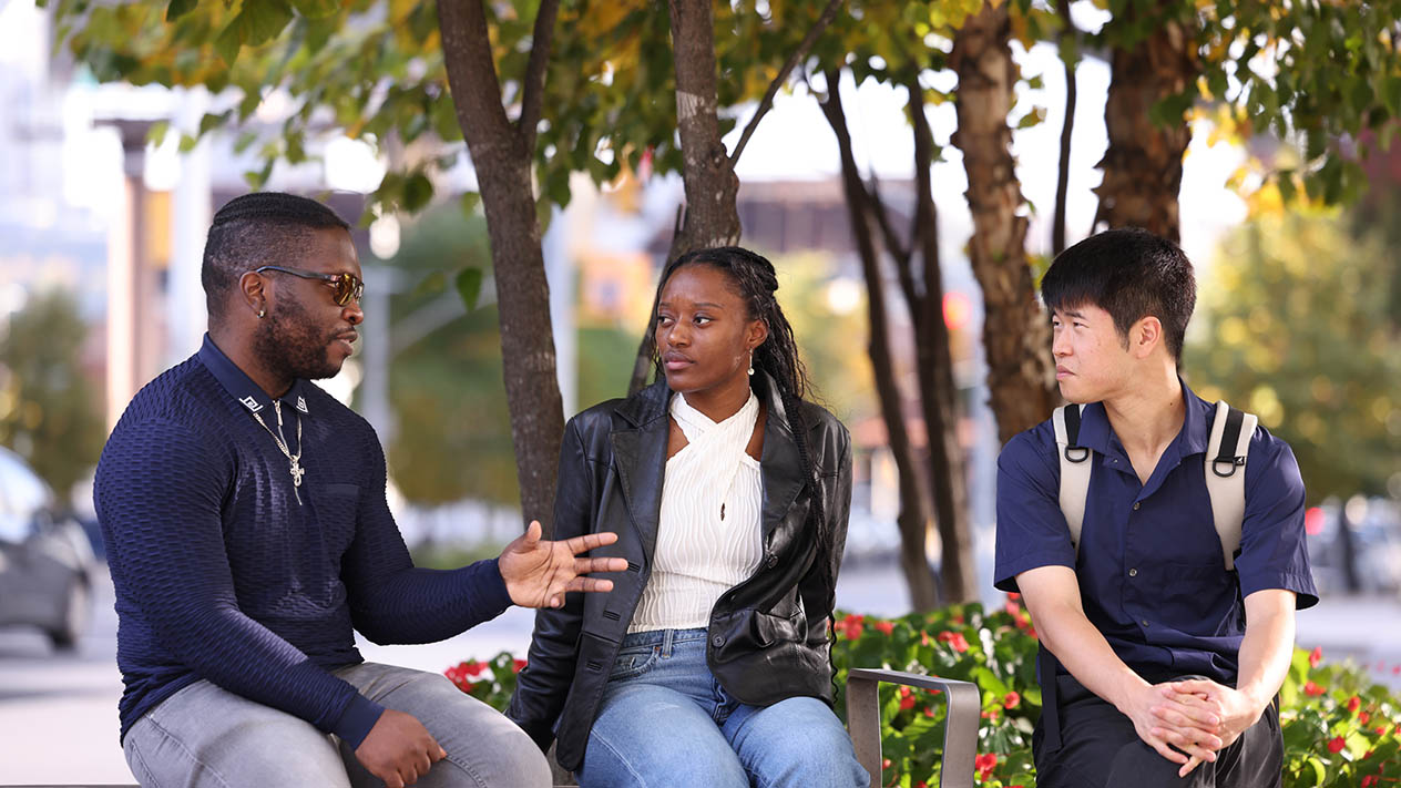 Three Columbia Engineering students sit and talk outdoors.
