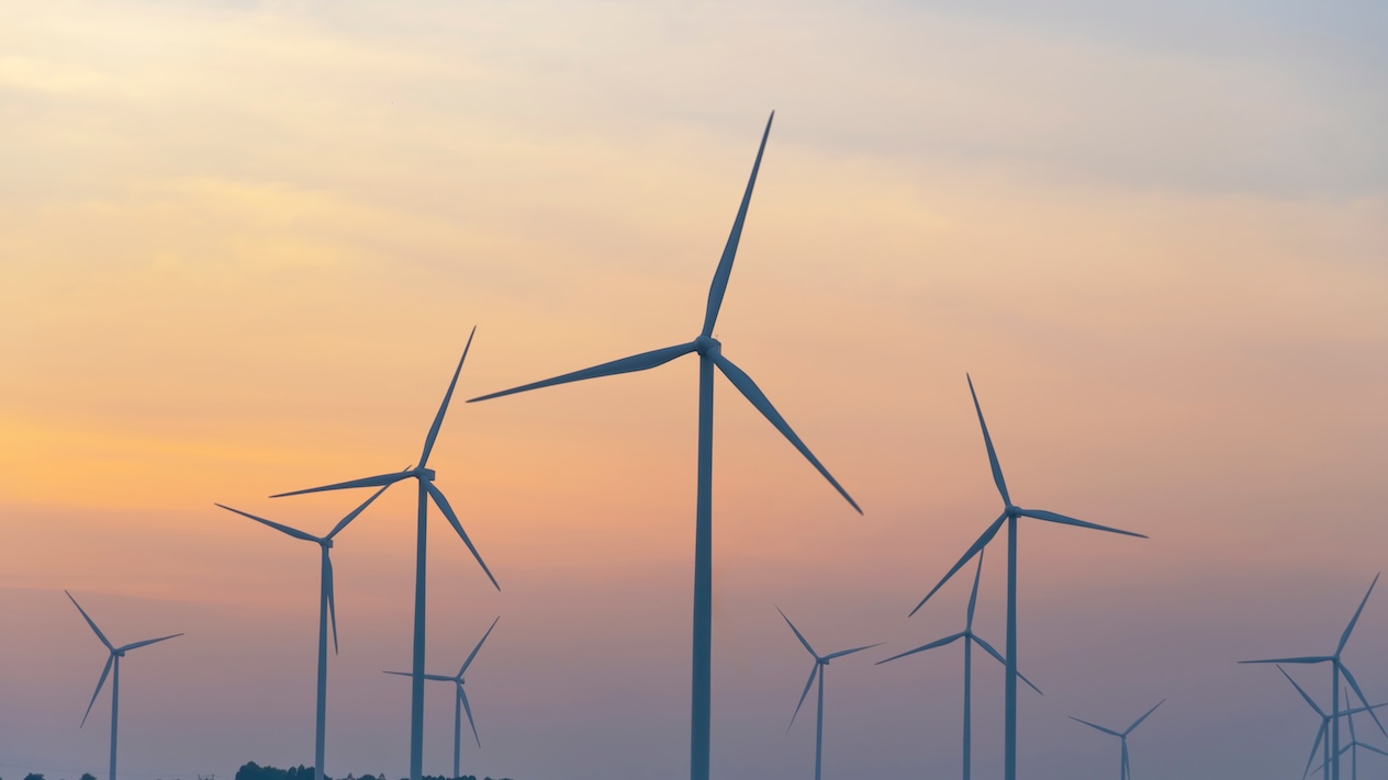 Wind turbines scattered across an orange sky