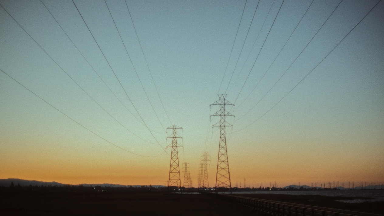 Power lines stretching toward the horizon over orange-blue skies