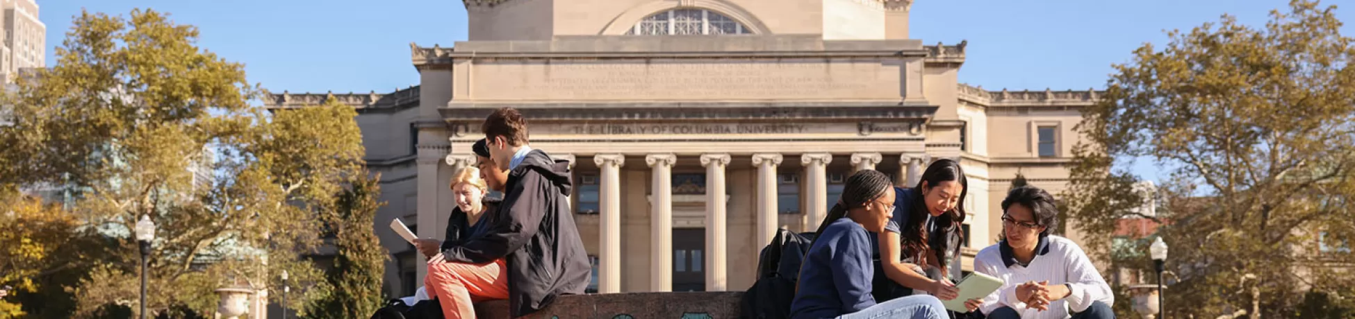 A group of students sit on the steps of Columbia University's campus.