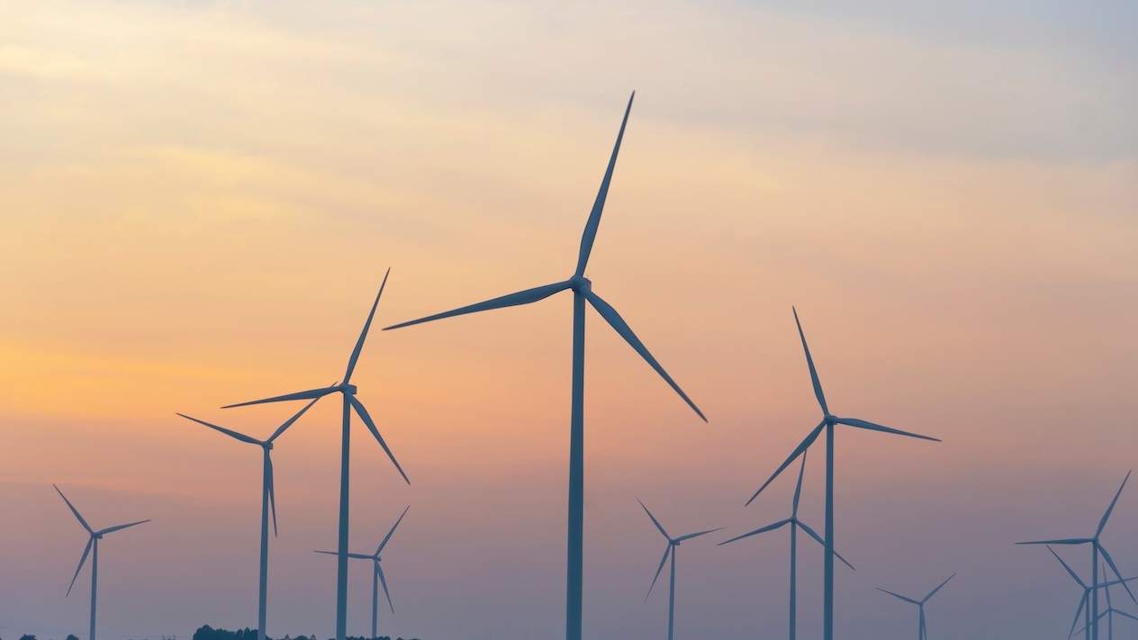 Wind turbines scattered across an orange sky